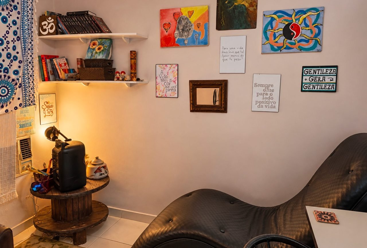 Sala de atendimento com divã, estante e quadros